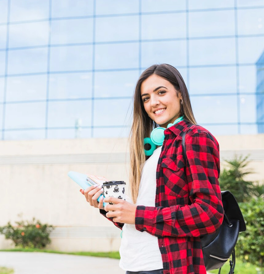 Smiling student holding coffee and notebook for study abroad agencies in kerala